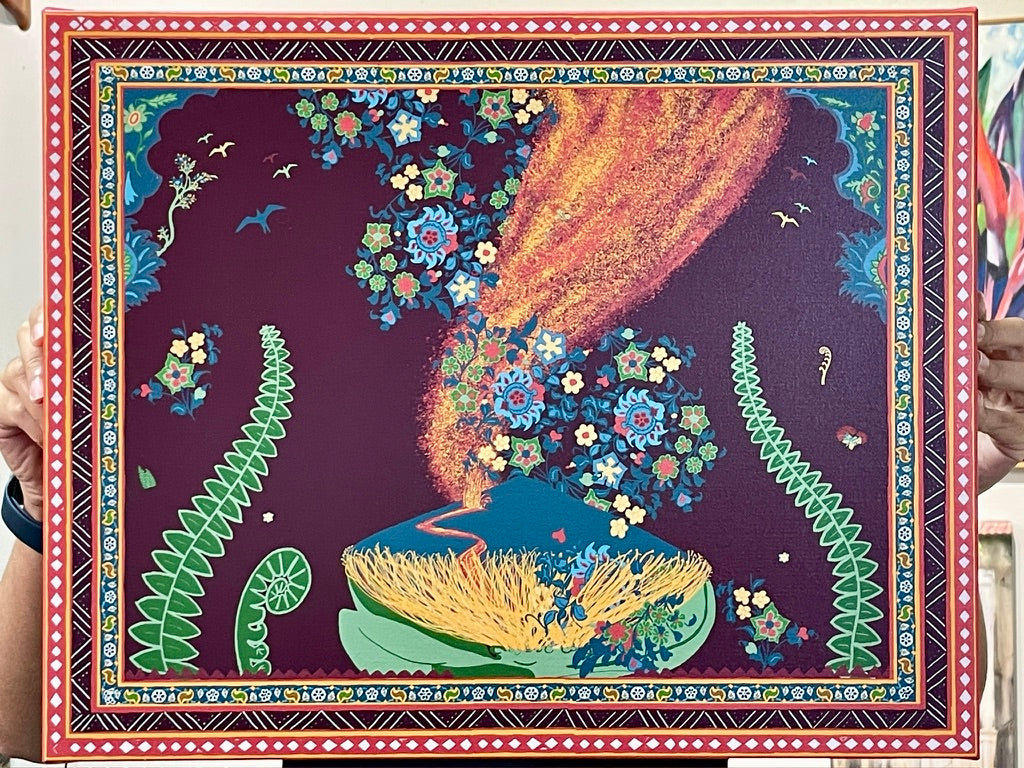 A colorful folk art print or painting depicting a cosmic scene with a bright orange and yellow celestial body falling through a dark purple sky filled with flowers, birds, and green fern-like motifs, framed by a decorative patterned border. Hands are holding the print on either side.